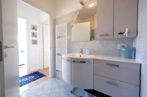 ein weißes Badezimmer mit einem Waschbecken und einem Spiegel in der Unterkunft GARDA BLUE HOME - Piscina, Solarium e Box in Toscolano-Maderno