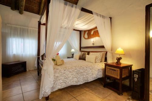 Elephants Footprint Lodge في كولشستر: غرفة نوم مع سرير كبير ذو مظلة مع ستائر