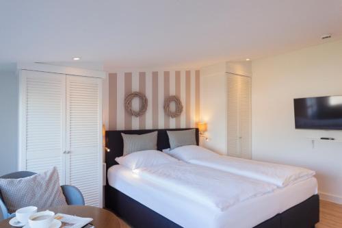 ein Schlafzimmer mit einem großen weißen Bett und einem Tisch in der Unterkunft Apartment an der Flensburger Förde in Munkbrarup