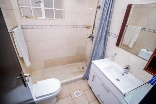 y baño con aseo, lavabo y ducha. en JCA APARTMENTS, en Nairobi