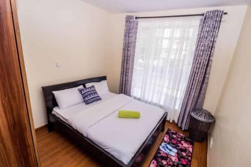 a small bedroom with a bed with a window at JCA APARTMENTS in Nairobi