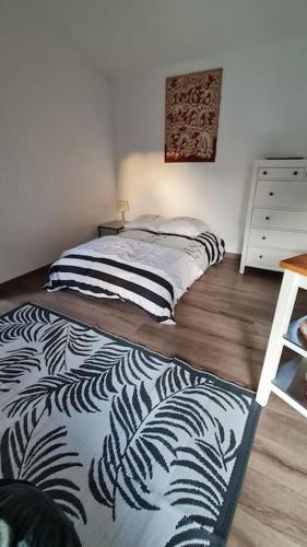 um quarto com uma cama com um cobertor preto e branco em Studio 1 à 2personnes em Nîmes