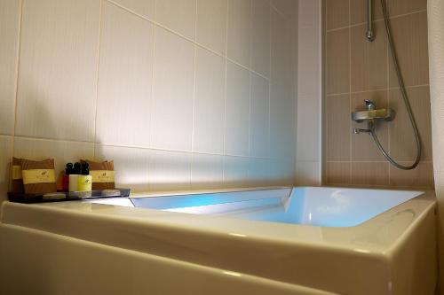 Tartu Rakendusliku Kolledži Hotell في تارتو: حوض استحمام في حمام مع دش