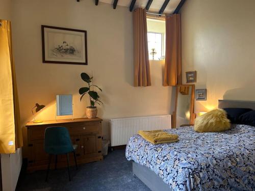 a bedroom with a bed and a desk and a chair at Twattleton Cottage Kilburn Yorkshire - Beautiful views in York