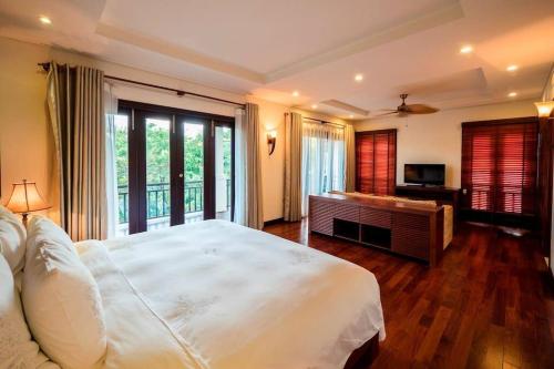 a bedroom with a large white bed and a balcony at 3BR garden pool villas in beach resort in Da Nang