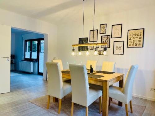 a dining room with a wooden table and white chairs at Allegra Appartements in Nohfelden