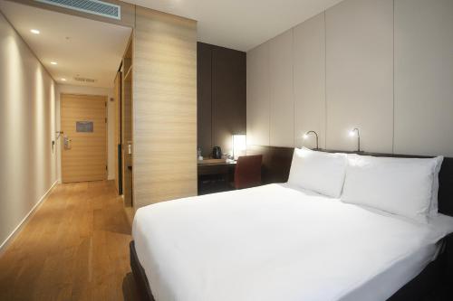 a bedroom with a large white bed and a desk at Crown Park Hotel Seoul Myeongdong in Seoul
