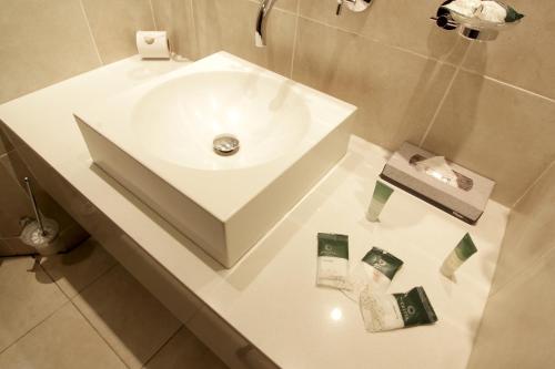 y baño con lavabo blanco y artículos de aseo en una encimera. en Cresta Lodge Gaborone en Gaborone