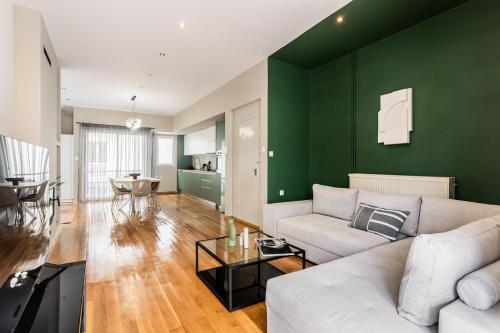 a living room with a white couch and a green wall at The Gate by Zoia Living in Athens