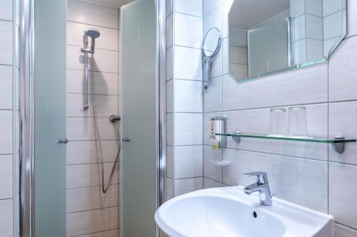 a white bathroom with a sink and a shower at Schlossberg-Hotel Garni in Wernigerode