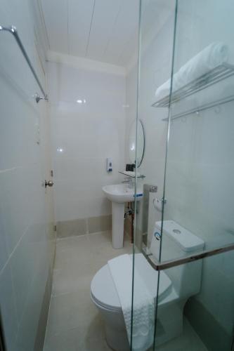 a white bathroom with a toilet and a sink at Balay Talisay in Balogo