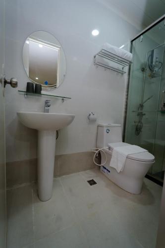 a bathroom with a sink and a toilet and a mirror at Balay Talisay in Balogo
