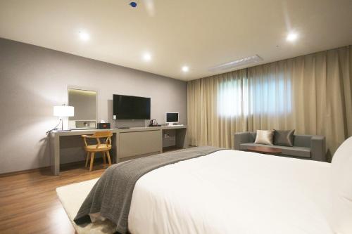 een slaapkamer met een bed, een bureau en een televisie bij Maruo Hotel in Naju