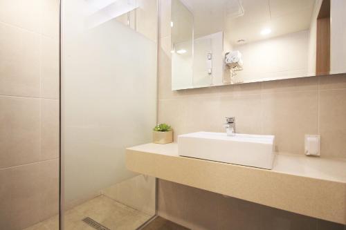 een badkamer met een witte wastafel en een douche bij Maruo Hotel in Naju