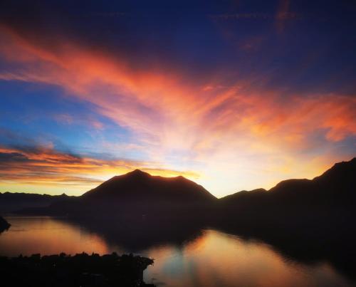 a sunset over a body of water with mountains at Il porticciolo in Bellano