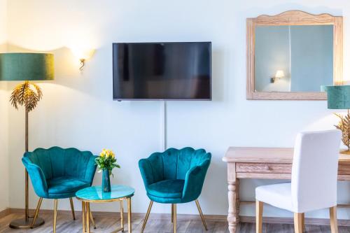 a living room with two chairs and a table and a tv at Schlossberg-Hotel Garni in Wernigerode