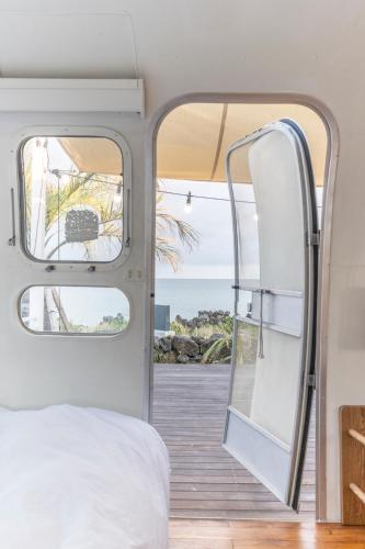 a bedroom with a bed and a view of the ocean at BeachBoys - Retro Caravan AirStream in Jeju