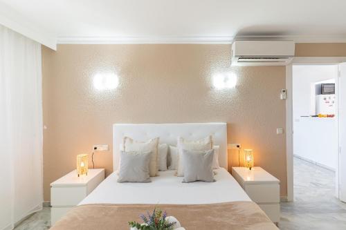 1 dormitorio con 1 cama blanca grande y 2 lámparas en MONKÓ BORA BORA, en Benalmádena