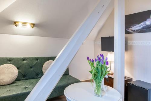 a living room with a green couch and a vase of purple flowers at Schlossberg-Hotel Garni in Wernigerode