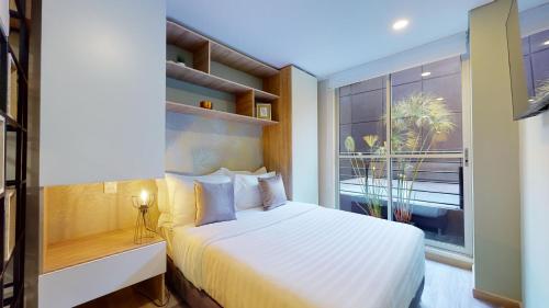 um quarto com uma cama branca e uma janela em Exclusivos Aptos amoblados en el edificio Cabrera 85-12 em Bogotá