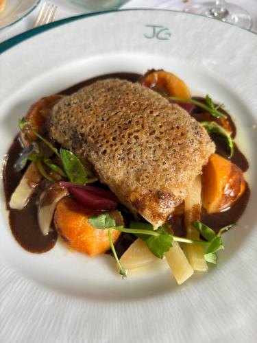 a plate of food with a piece of fish and vegetables at Logis Hotel L'Embarcadère in Nantua