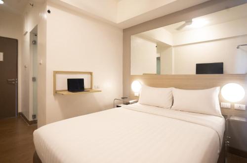 1 dormitorio con cama blanca y espejo en Red Planet Manila Malate Mabini, en Manila