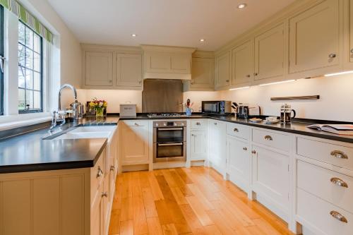 a kitchen with white cabinets and a wooden floor at Charlton Down Cottage in Tetbury