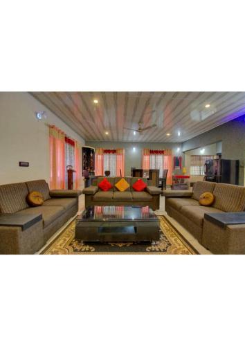 a large living room with couches and a table at Sriniketana Homestay in Madikeri