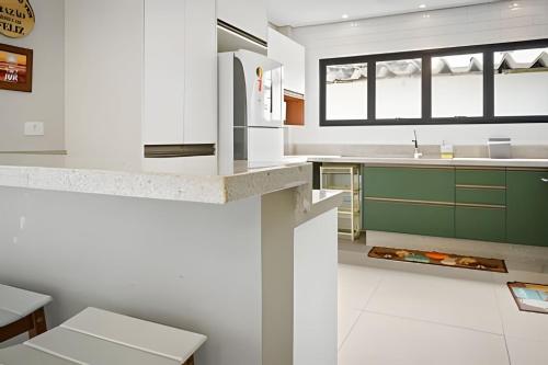 a kitchen with white counters and green cabinets at bwelcome - pé na areia com piscina GH in Bertioga