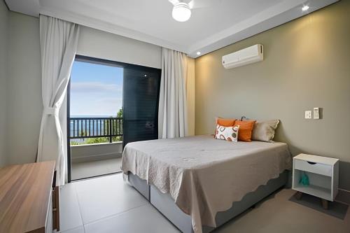 a bedroom with a bed and a balcony at bwelcome - pé na areia com piscina GH in Bertioga
