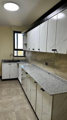a kitchen with white cabinets and granite counter tops at Annaye Apartment in Addis Ababa