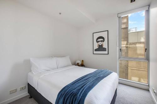 een witte slaapkamer met een bed en een raam bij The Sweet Escape - Chic Apartment with Rooftop Pool in Melbourne