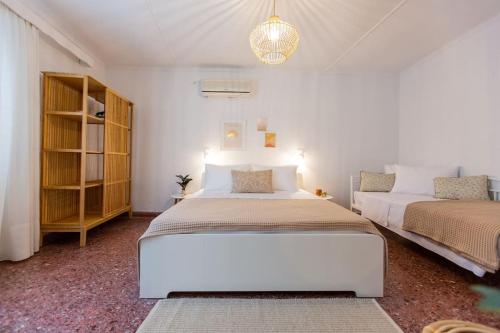 um quarto branco com 2 camas e um lustre em Μονοκατοικία - The Olive Tree em Lepanto