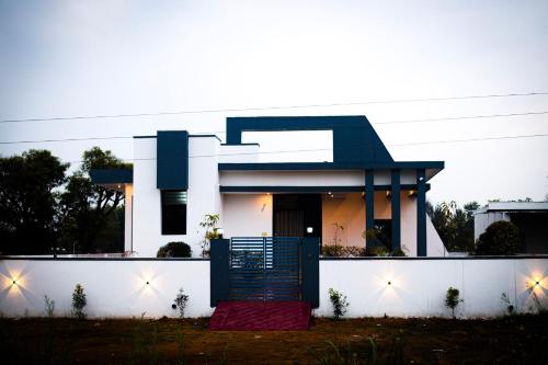 een huis met een blauwe deur en een witte muur bij Luxuria Farmstays in Jaipur