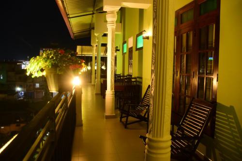 a building with chairs and a porch at night at Grand View Guest House in Haputale