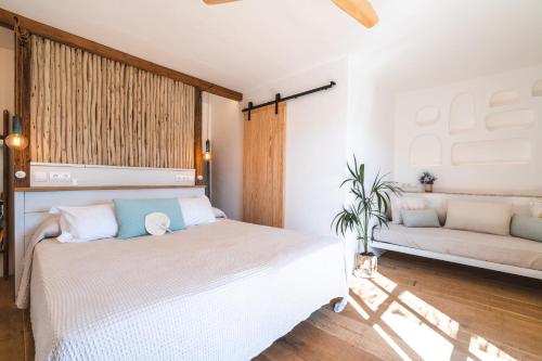 a bedroom with a white bed and a couch at ES CUCONS RURAL HOTEL in San Antonio