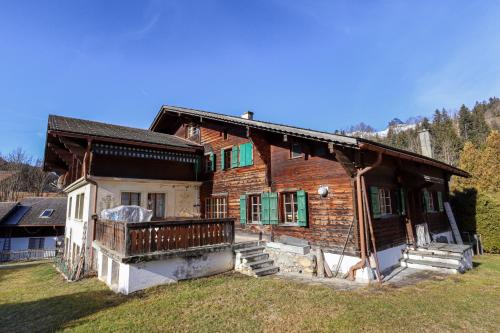 a wooden house with green shutters and a yard at Chalet Marie-José in Chateau-d'Oex