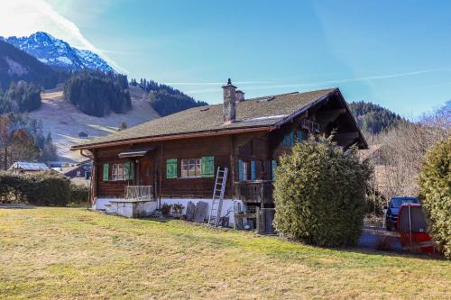 une maison sur une colline avec une montagne en arrière-plan dans l'établissement Chalet Marie-José, à Château-d'Oex