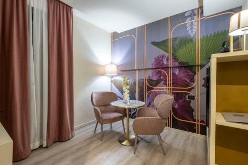 a room with a table and chairs and a painting at Hotel Le Palme in Dormelletto
