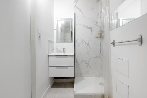une salle de bain blanche avec une douche et un lavabo dans l'établissement Cosy T2, terrasse privée et Parking, à Toulouse