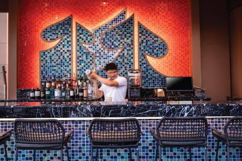 a man standing behind a bar in a restaurant at SAMALA Hotel Bangkok in Bangkok