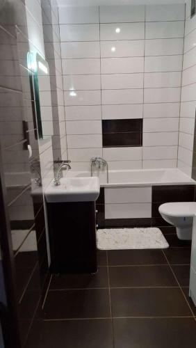 ein Badezimmer mit einem Waschbecken, einer Badewanne und einem WC in der Unterkunft Nero in Mrągowo