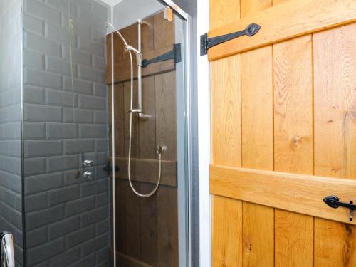 a shower in a bathroom with a wooden door at Viking Cottage in Lochailort