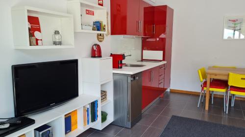 een keuken met rode kasten en een flatscreen-tv bij Quinta Paúl de Baixo in Guimarães