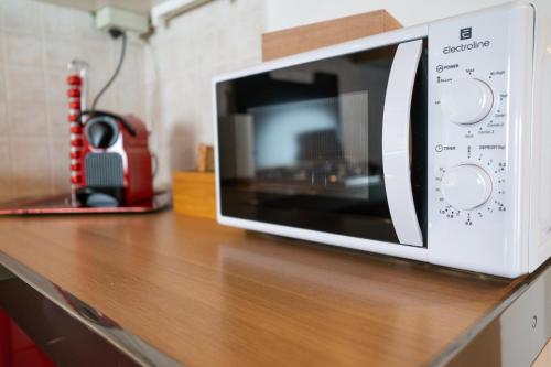 a microwave sitting on top of a wooden counter at Incantevole Mansardato 75mq vicino a BGY in Zanica