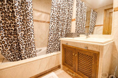 La salle de bains est pourvue d'un lavabo et d'un rideau de douche. dans l'établissement Costalita Apartment - Pool by the Beach, à Estepona