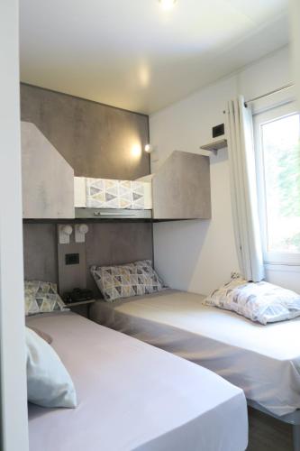 2 camas en una habitación pequeña con ventana en Camping Adriatico, en Martinsicuro