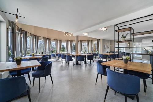 un restaurant avec des tables, des chaises et des fenêtres dans l'établissement Hotel Arborétum Harkány, à Harkány