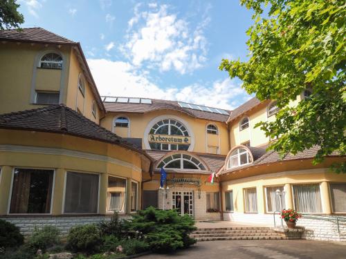 d'un grand bâtiment jaune avec un panneau. dans l'établissement Hotel Arborétum Harkány, à Harkány