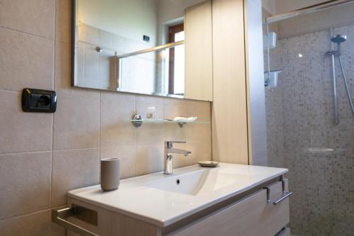a bathroom with a sink and a mirror and a shower at Incantevole Mansardato 75mq vicino a BGY in Zanica